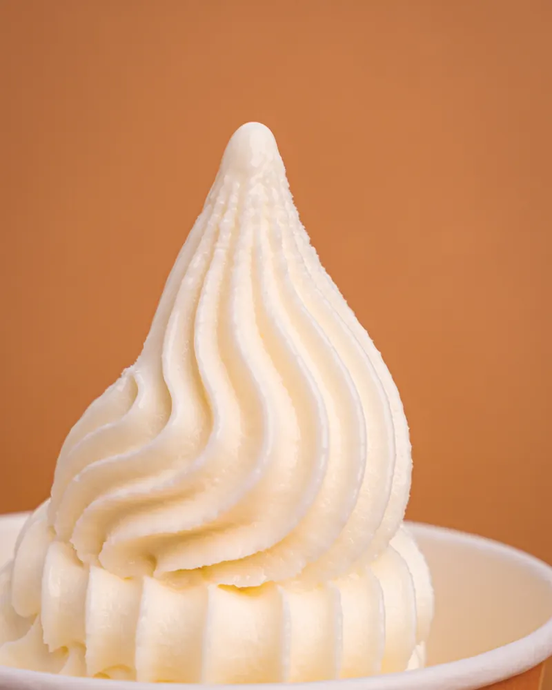 Helado de yogurt natural recién servido, en remolino, sobre fondo naranja